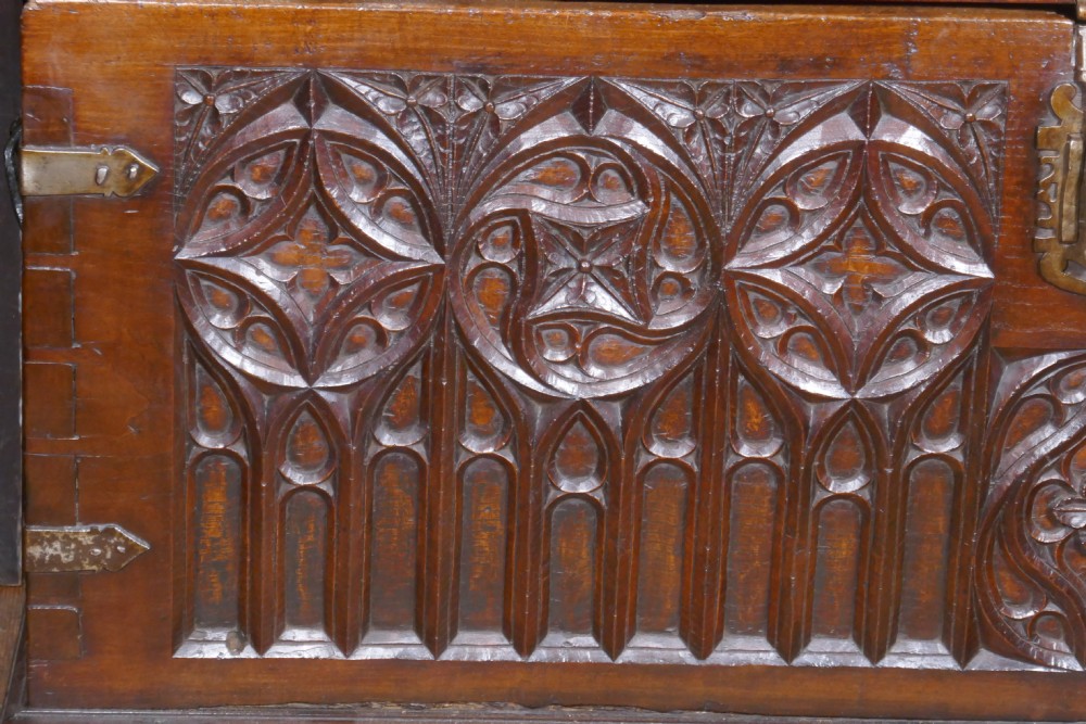 A dark oak 16th-century coffer featuring carved Gothic tracery panels and a central iron lock mechanism. View IX