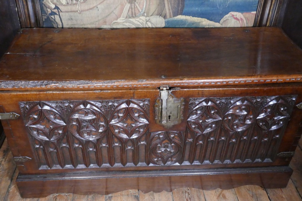 A dark oak 16th-century coffer featuring carved Gothic tracery panels and a central iron lock mechanism. View XI