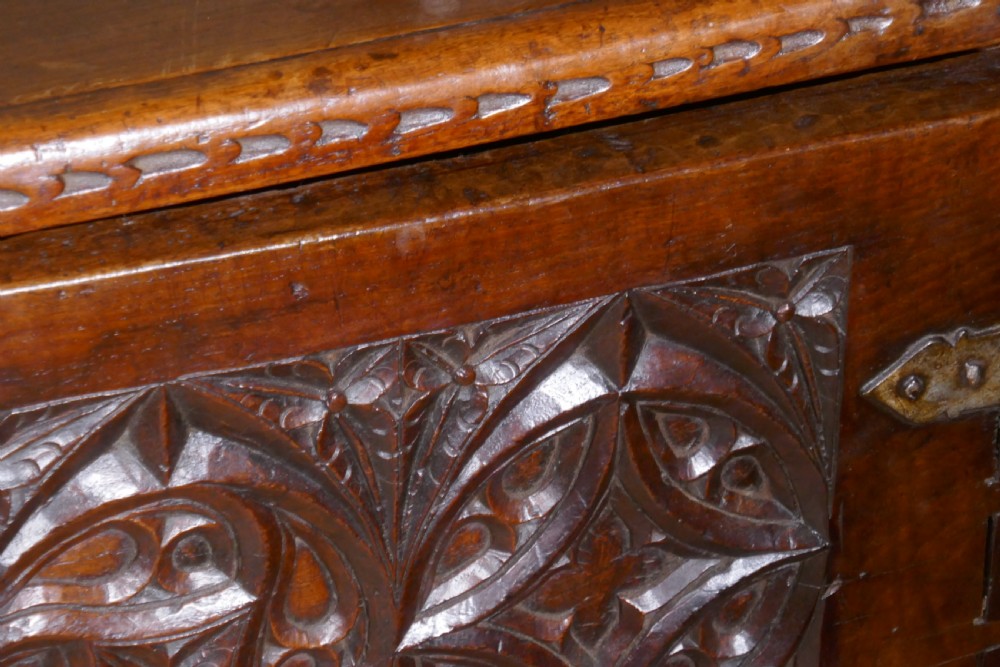 A dark oak 16th-century coffer featuring carved Gothic tracery panels and a central iron lock mechanism. View XII