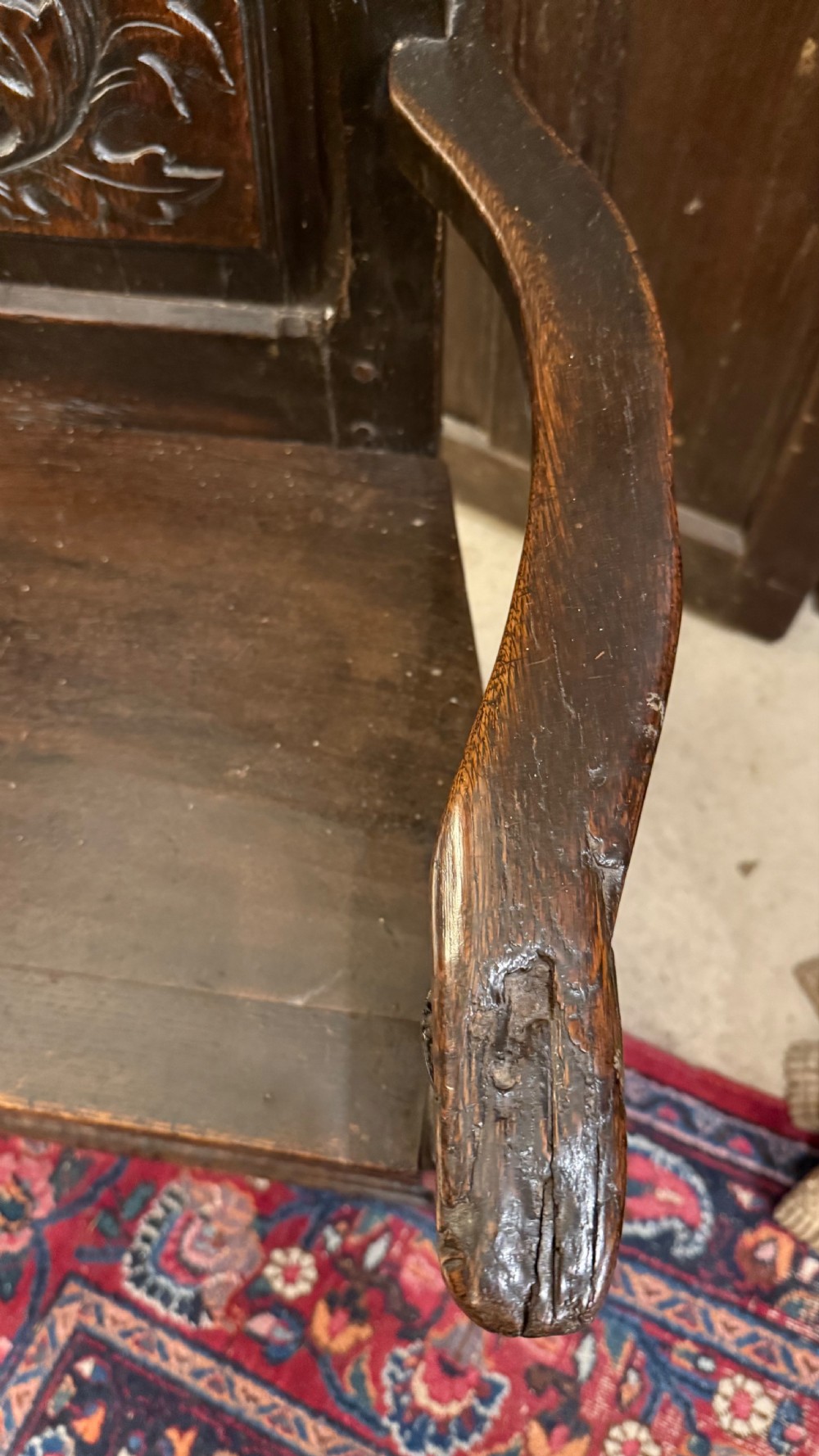 A 17th-century dark oak wainscot armchair with a carved thistle back panel, carved top crest, and turned legs. View XI