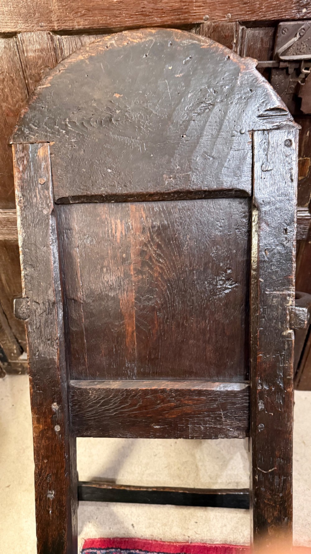 A 17th-century dark oak wainscot armchair with a carved thistle back panel, carved top crest, and turned legs. View XVII