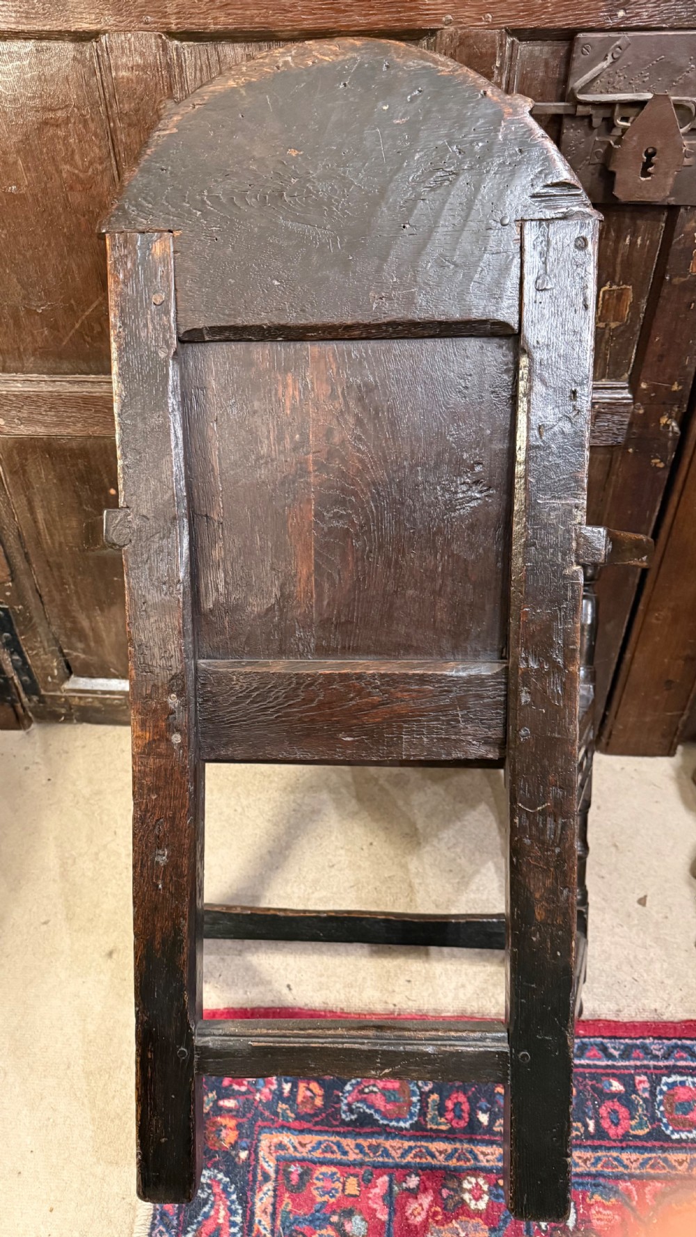 A 17th-century dark oak wainscot armchair with a carved thistle back panel, carved top crest, and turned legs. View XVIII