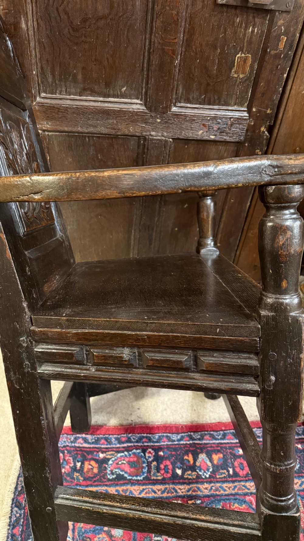 A 17th-century dark oak wainscot armchair with a carved thistle back panel, carved top crest, and turned legs. View XIX