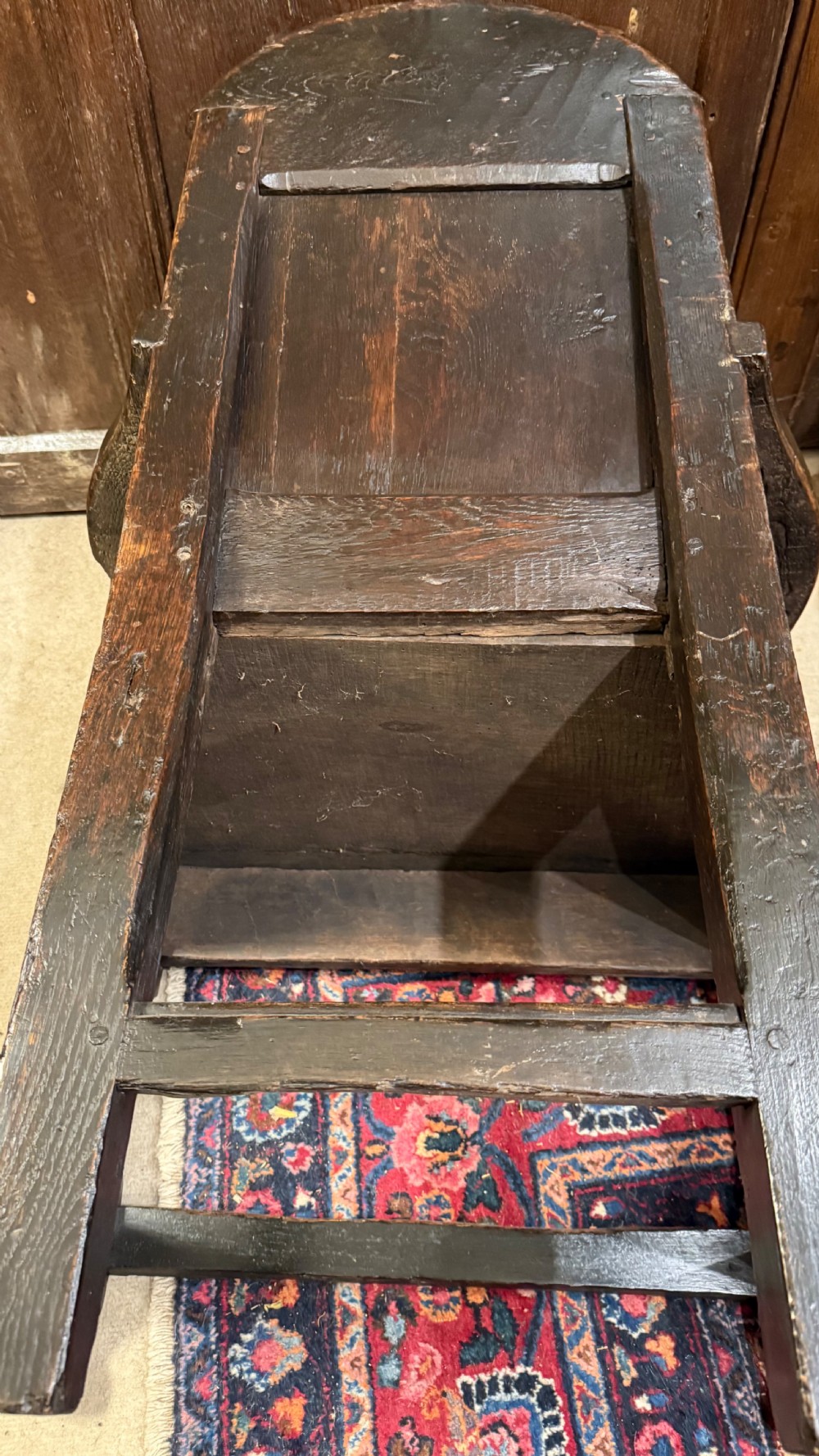 A 17th-century dark oak wainscot armchair with a carved thistle back panel, carved top crest, and turned legs. View XX