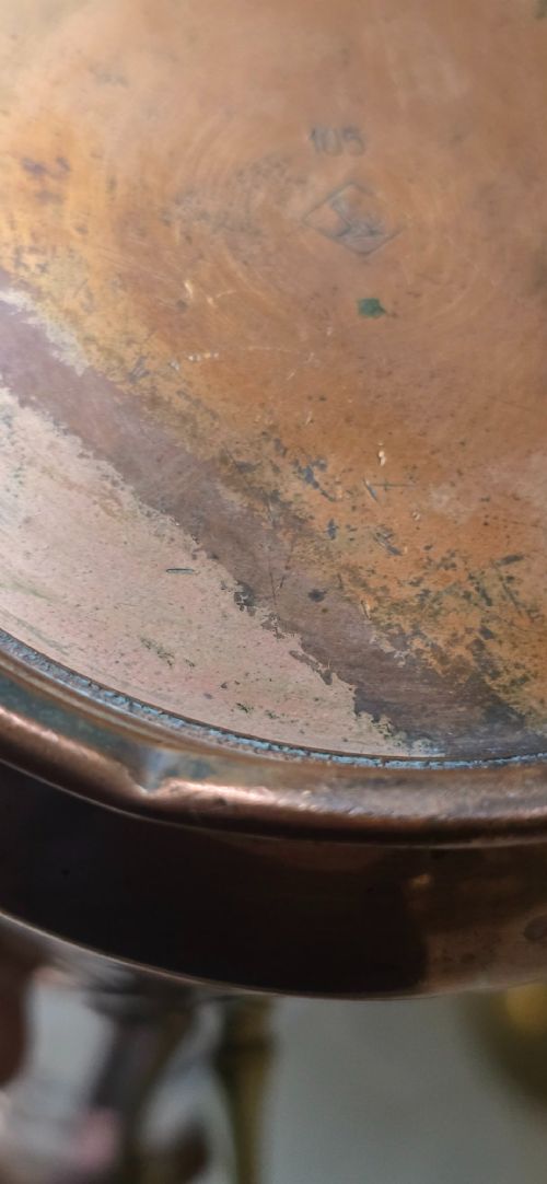 fig 3. An Art Nouveau tapered copper ewer with a raised floral relief pattern, angular brass handle, hinged brass cap, and subtle dark circular motifs near the base.