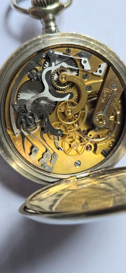 fig 5. An open-face military pocket watch chronograph featuring a white enamel dial with black Arabic numerals, dual sub-dials, and French military markings enclosed in a round silver case.