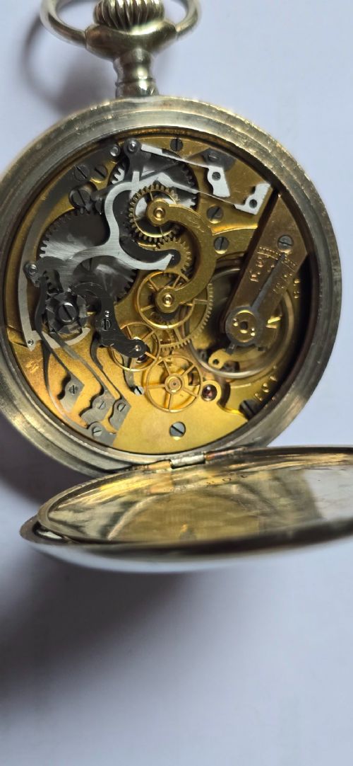 fig 6. An open-face military pocket watch chronograph featuring a white enamel dial with black Arabic numerals, dual sub-dials, and French military markings enclosed in a round silver case.