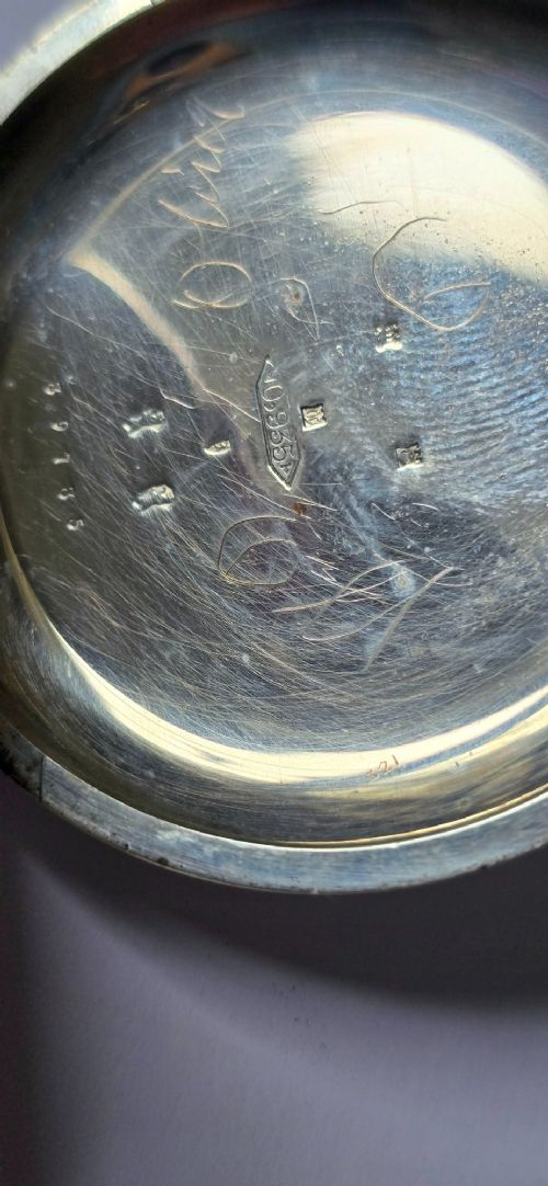 fig 4. An open-face silver pocket watch featuring a white enamel dial with black Roman numerals, split-seconds hands, a subsidiary seconds dial, and a brass onion crown at the top.