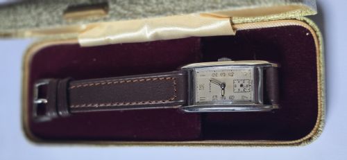 fig 2. A 1940s rectangular gents mechanical tank watch with a silver-tone case, cream dial featuring printed Arabic numerals and a sub-seconds dial, finished with a brown leather strap.