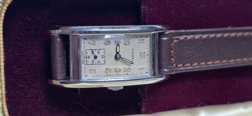 fig 3. A 1940s rectangular gents mechanical tank watch with a silver-tone case, cream dial featuring printed Arabic numerals and a sub-seconds dial, finished with a brown leather strap.