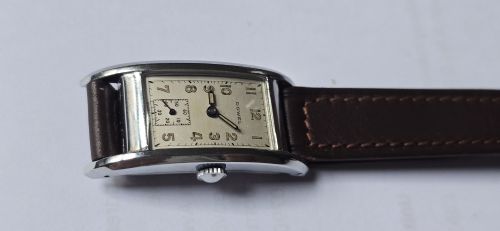 fig 8. A 1940s rectangular gents mechanical tank watch with a silver-tone case, cream dial featuring printed Arabic numerals and a sub-seconds dial, finished with a brown leather strap.