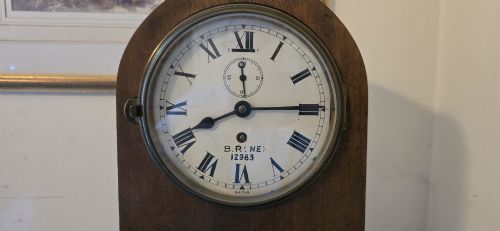 fig 1. An arched wooden mantel clock featuring a white dial with Roman numerals, a brass bezel, and British Rail markings.