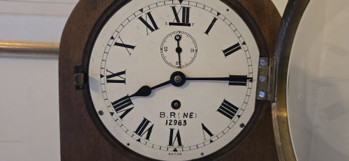 fig 3. An arched wooden mantel clock featuring a white dial with Roman numerals, a brass bezel, and British Rail markings.