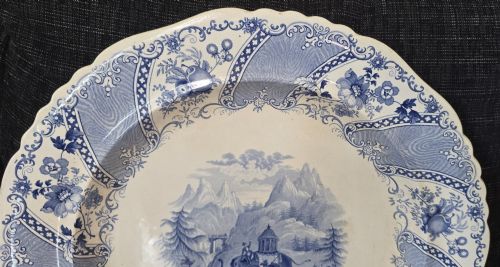 fig 3. An antique circular earthenware plate featuring a blue transfer-printed central scene of Hannibal with an elephant and figures in a mountainous landscape, surrounded by an ornate scalloped floral border.