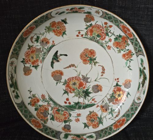 fig 2. A circular Chinese famille verte porcelain dish featuring hand-painted peony blossoms, foliage, a bird in flight, and a decorative patterned border.