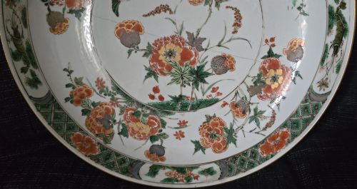 fig 3. A circular Chinese famille verte porcelain dish featuring hand-painted peony blossoms, foliage, a bird in flight, and a decorative patterned border.