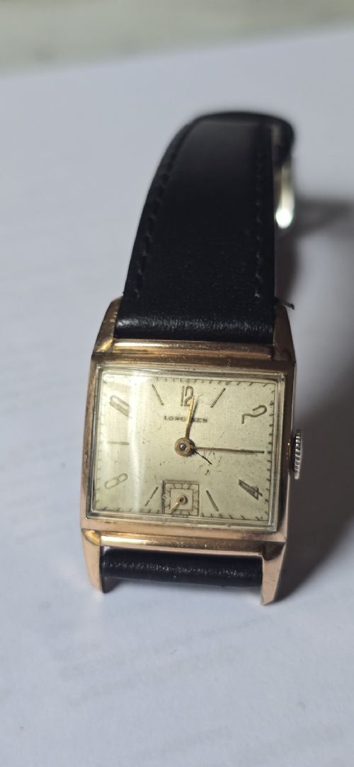 fig 1. A vintage Longines rectangular wristwatch featuring a rose gold-filled case, patinated dial with Arabic numerals, sub-seconds register, and a black leather strap.