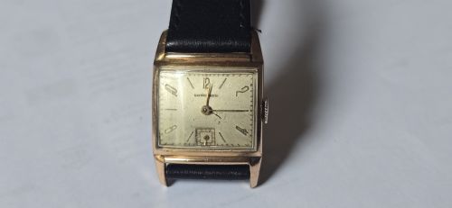 fig 2. A vintage Longines rectangular wristwatch featuring a rose gold-filled case, patinated dial with Arabic numerals, sub-seconds register, and a black leather strap.