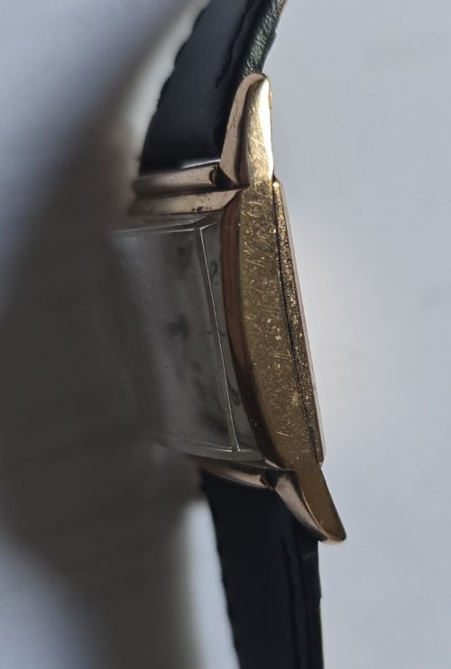 fig 5. A vintage Longines rectangular wristwatch featuring a rose gold-filled case, patinated dial with Arabic numerals, sub-seconds register, and a black leather strap.