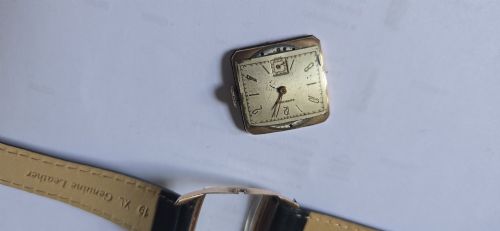 fig 6. A vintage Longines rectangular wristwatch featuring a rose gold-filled case, patinated dial with Arabic numerals, sub-seconds register, and a black leather strap.