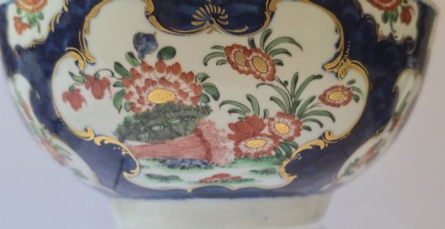 fig 1. An eighteenth-century circular porcelain bowl featuring a blue scale ground, gilded rococo cartouches, and hand-painted Kakiemon floral panels.