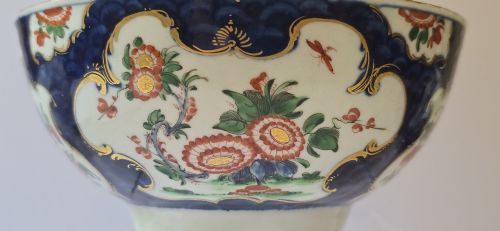 fig 2. An eighteenth-century circular porcelain bowl featuring a blue scale ground, gilded rococo cartouches, and hand-painted Kakiemon floral panels.