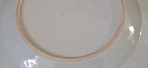 fig 3. A pair of circular white porcelain plates hand-painted with famille rose enamels depicting figures in an interior and garden setting with a floral rim border.