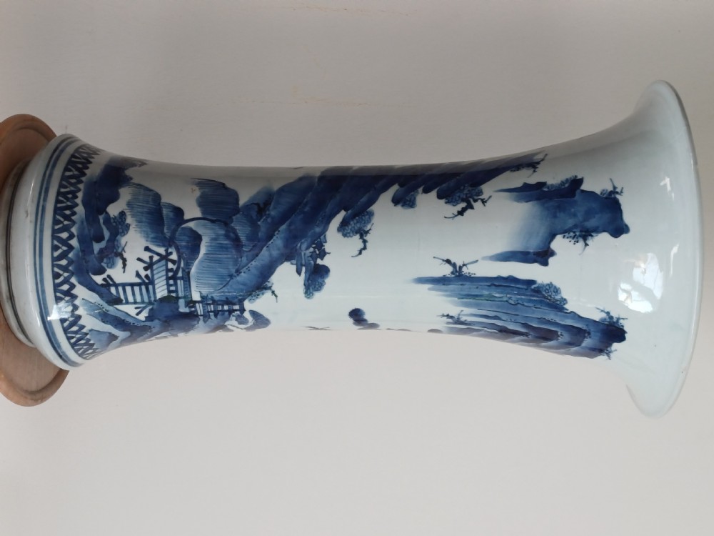 A tall Japanese Arita blue and white porcelain beaker vase featuring a flared trumpet rim and painted Kano style landscape motifs. View V