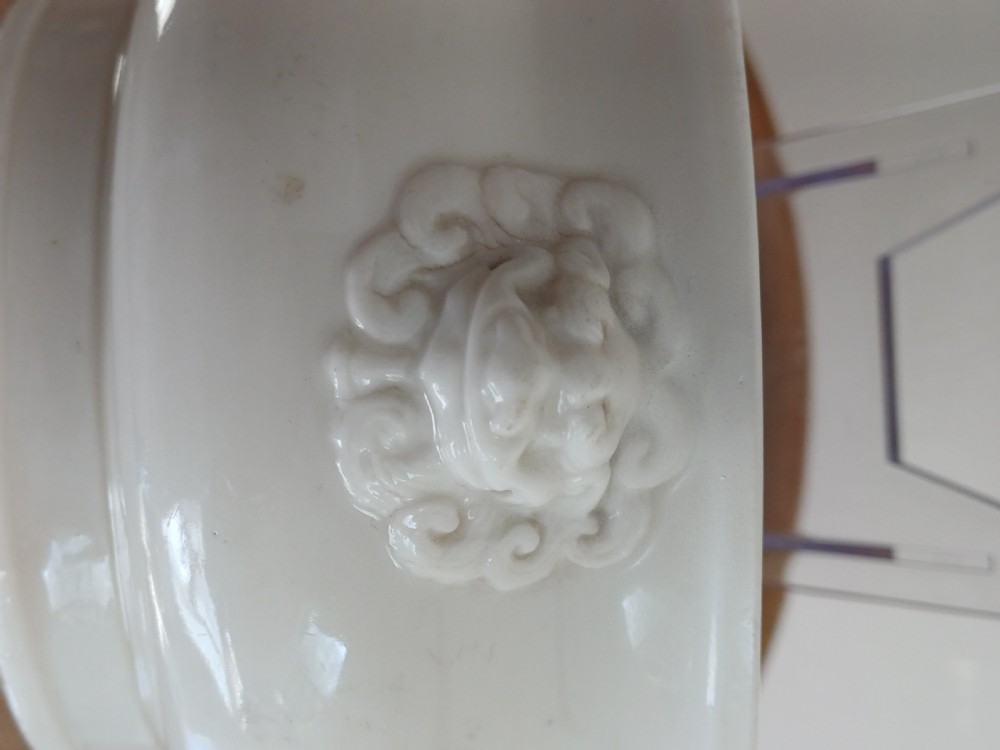 A small round ivory white glazed porcelain censer featuring moulded mask handles on either side and a short flared foot base. View V
