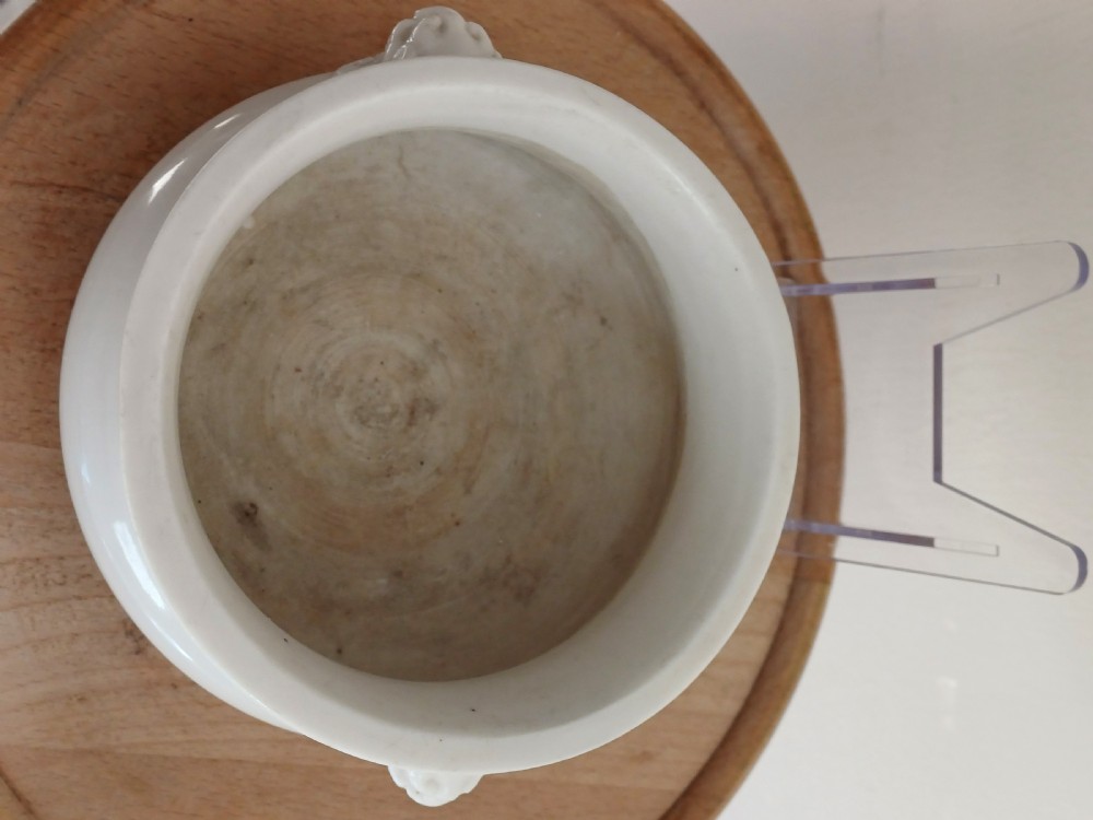 A small round ivory white glazed porcelain censer featuring moulded mask handles on either side and a short flared foot base. View X