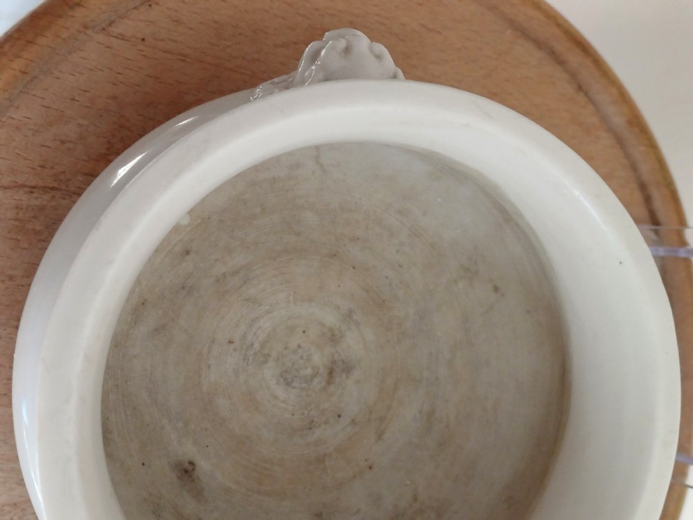 A small round ivory white glazed porcelain censer featuring moulded mask handles on either side and a short flared foot base. View XII