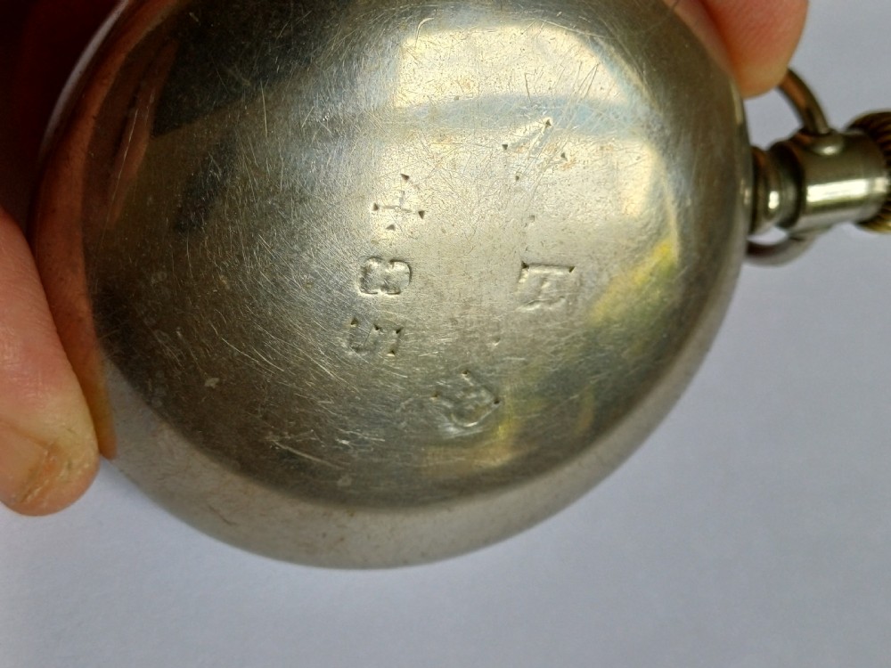 An open-face antique pocket watch featuring a white enamel dial with black Roman numerals, a sub-seconds dial, and a silver-tone nickel case. View VII
