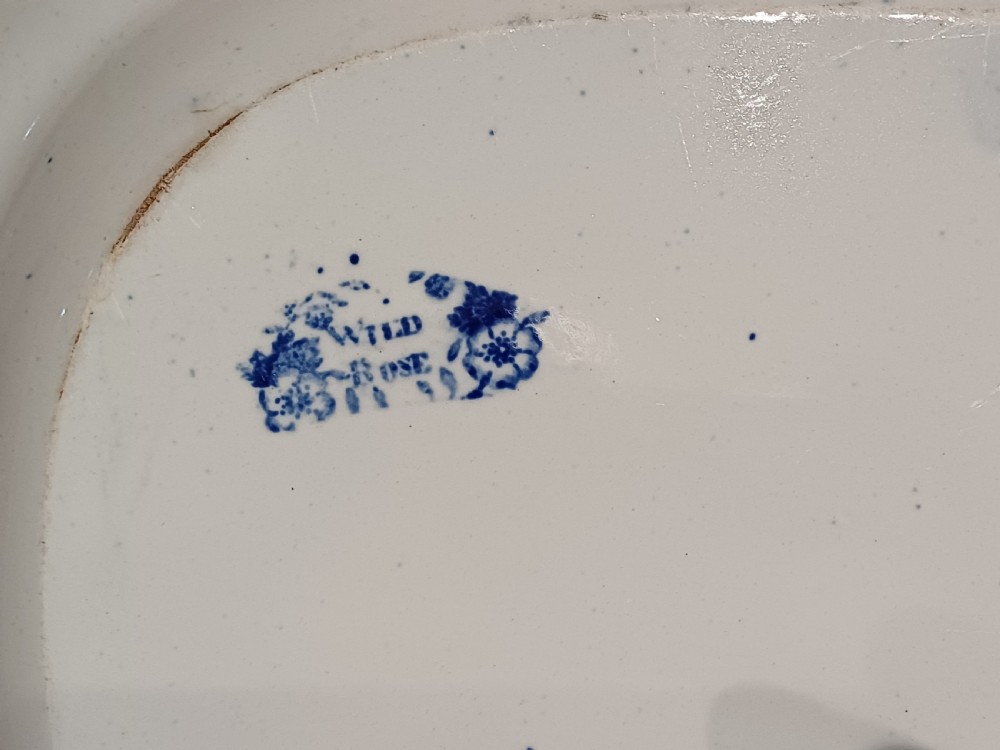 A large Victorian oval earthenware platter decorated with a cobalt blue and white transfer print featuring a pastoral river scene and a wide floral border. View IX