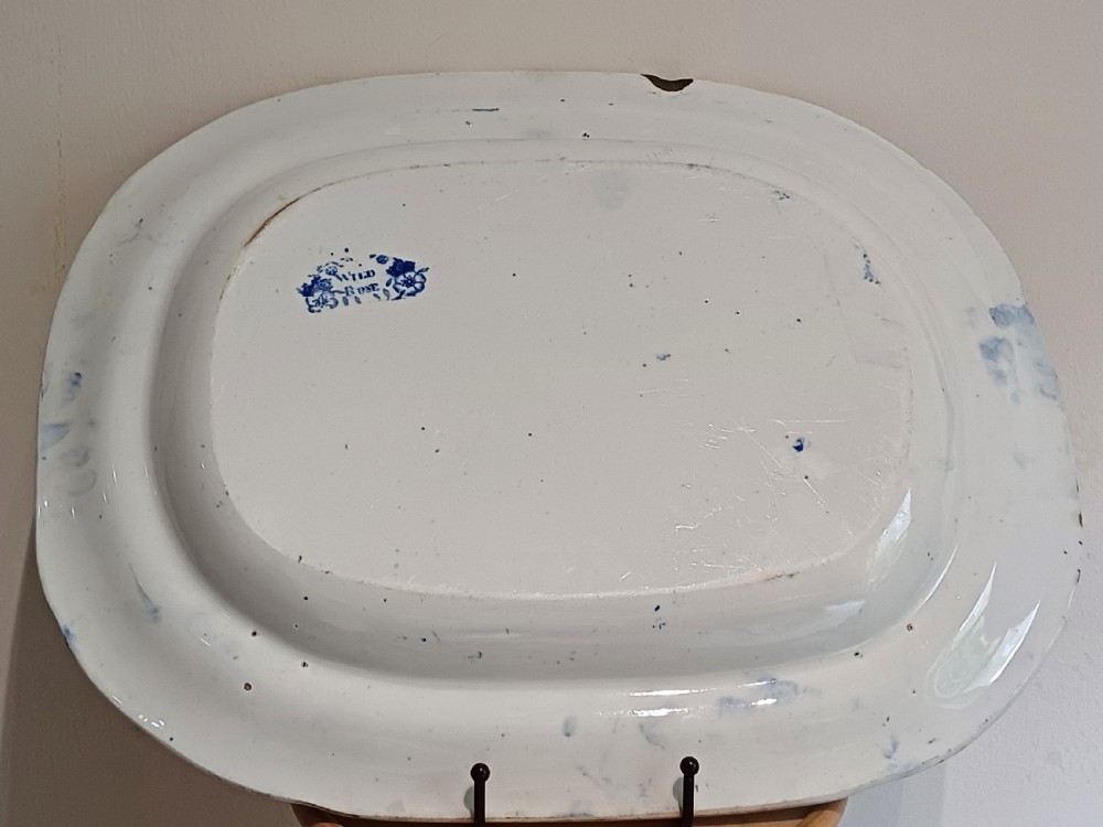 A large Victorian oval earthenware platter decorated with a cobalt blue and white transfer print featuring a pastoral river scene and a wide floral border. View XIII