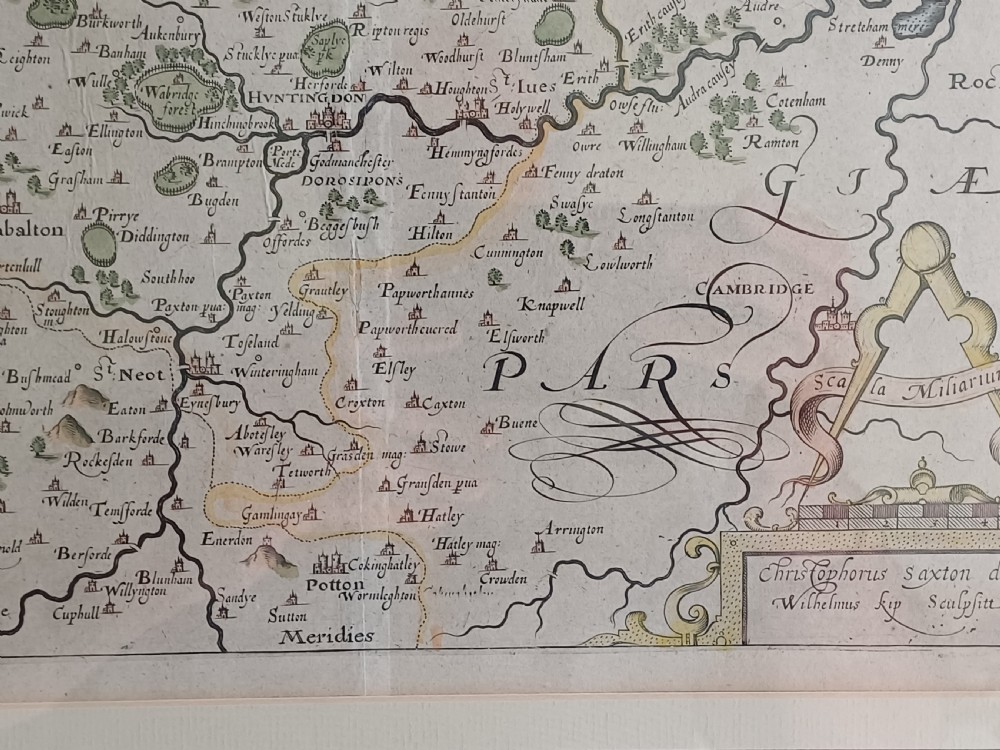 A framed 17th-century hand-coloured map of Huntingdon by Christopher Saxton set within an off-white mount and slim gilded frame. View VI