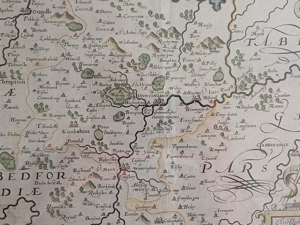 A framed 17th-century hand-coloured map of Huntingdon by Christopher Saxton set within an off-white mount and slim gilded frame. View XII