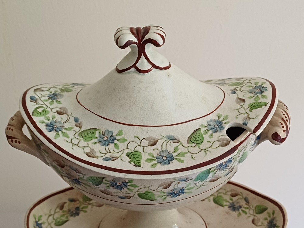 An antique cream earthenware pedestal dessert tureen with matching lid and stand, decorated with a floral vine border in blue and green. View III