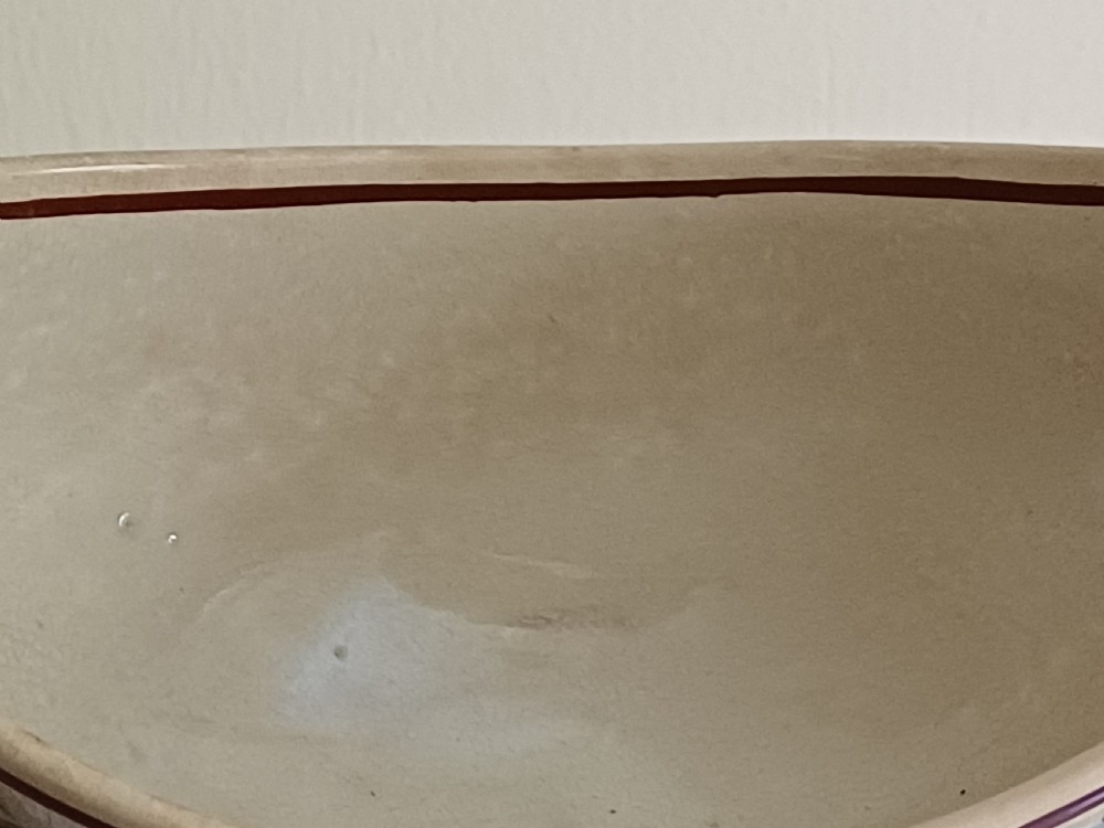 An antique cream earthenware pedestal dessert tureen with matching lid and stand, decorated with a floral vine border in blue and green. View X