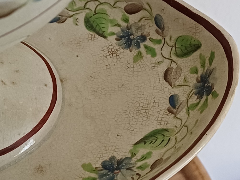 An antique cream earthenware pedestal dessert tureen with matching lid and stand, decorated with a floral vine border in blue and green. View XIII