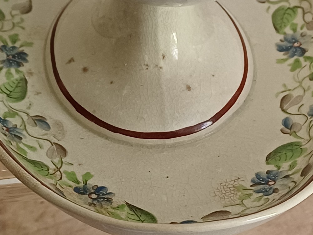 An antique cream earthenware pedestal dessert tureen with matching lid and stand, decorated with a floral vine border in blue and green. View XVI