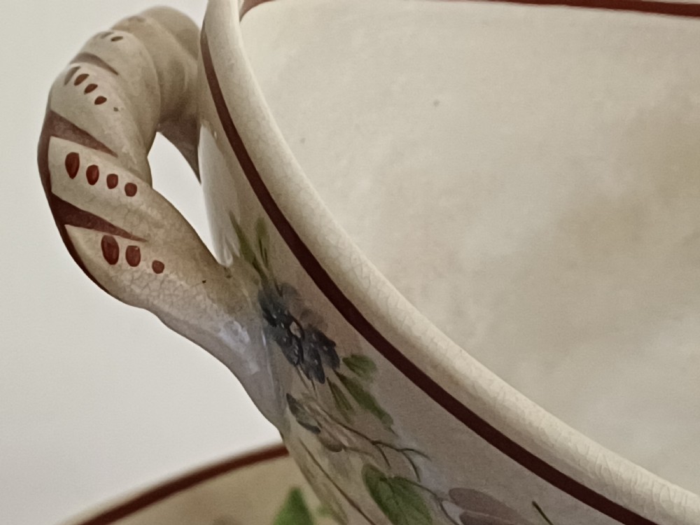 An antique cream earthenware pedestal dessert tureen with matching lid and stand, decorated with a floral vine border in blue and green. View XVIII