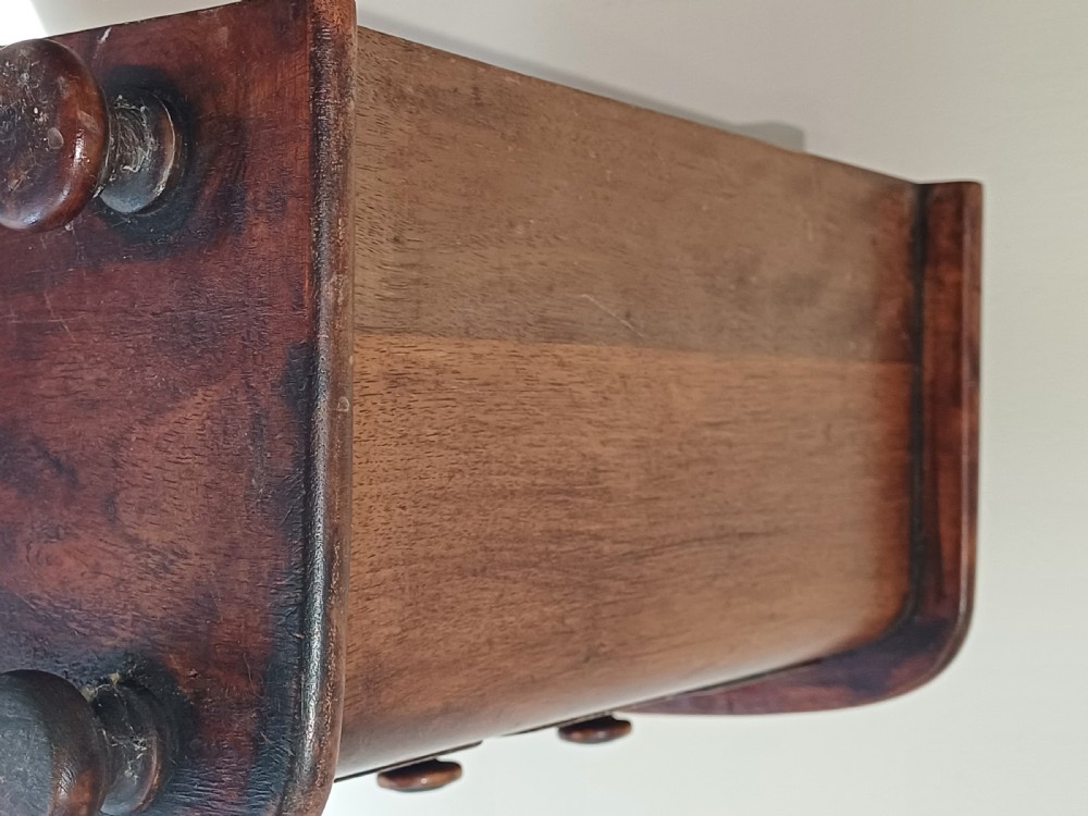 A Victorian miniature bow-fronted mahogany chest featuring three graduated drawers with turned wood knobs and bun feet. View XV