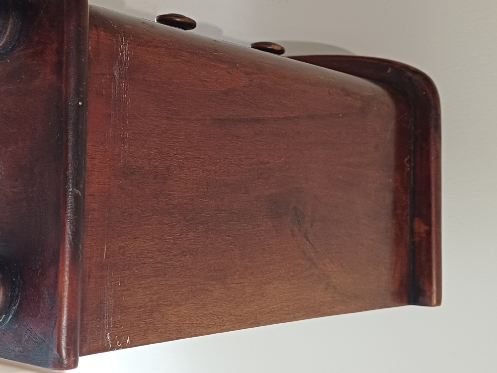 A Victorian miniature bow-fronted mahogany chest featuring three graduated drawers with turned wood knobs and bun feet. View XVI