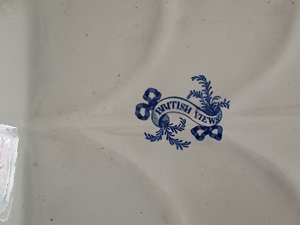A large oval blue and white transfer printed earthenware meat platter featuring a country landscape scene with a dog and a moulded gravy well channel. View X