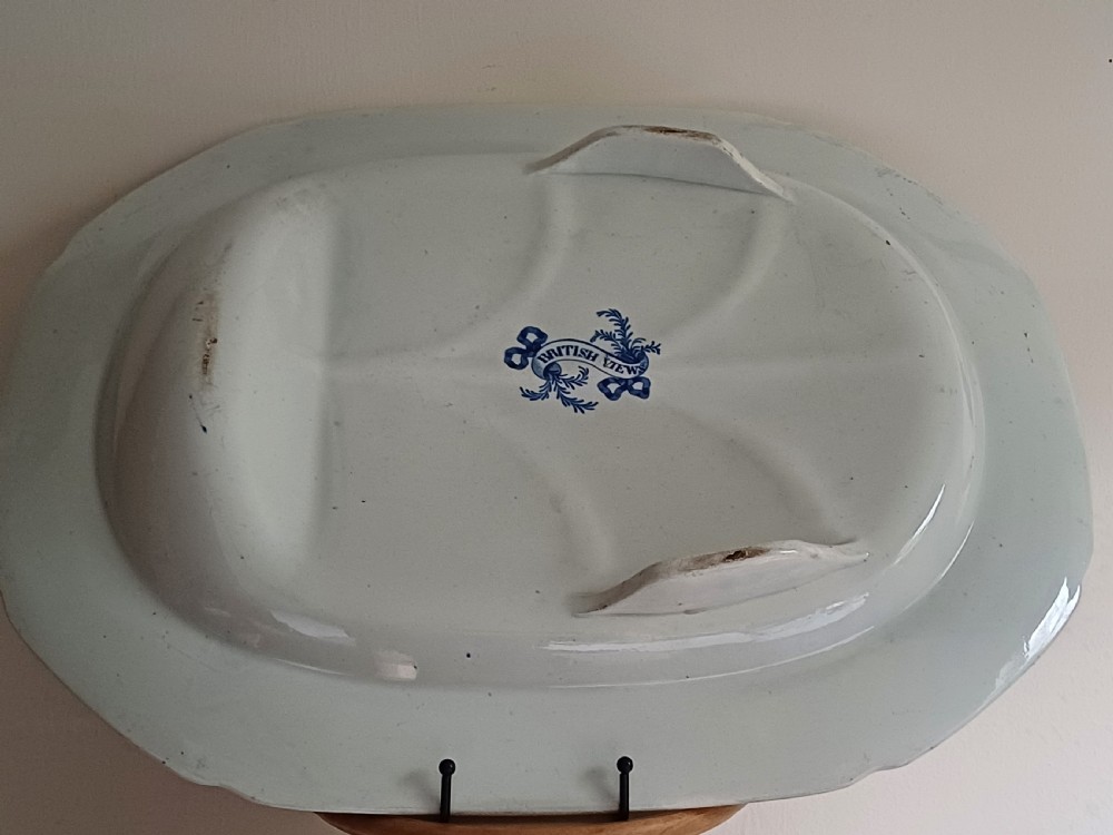 A large oval blue and white transfer printed earthenware meat platter featuring a country landscape scene with a dog and a moulded gravy well channel. View XII