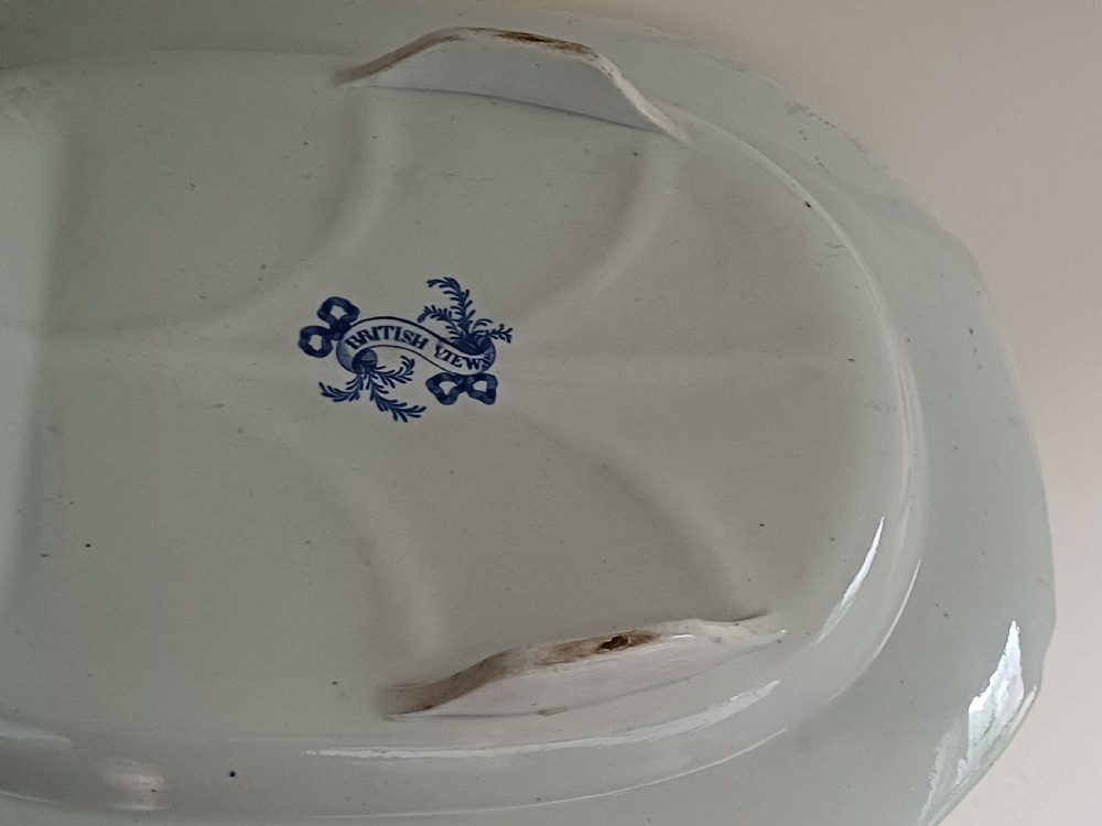 A large oval blue and white transfer printed earthenware meat platter featuring a country landscape scene with a dog and a moulded gravy well channel. View XVI