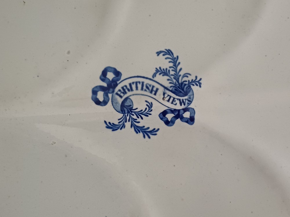 A large oval blue and white transfer printed earthenware meat platter featuring a country landscape scene with a dog and a moulded gravy well channel. View XX