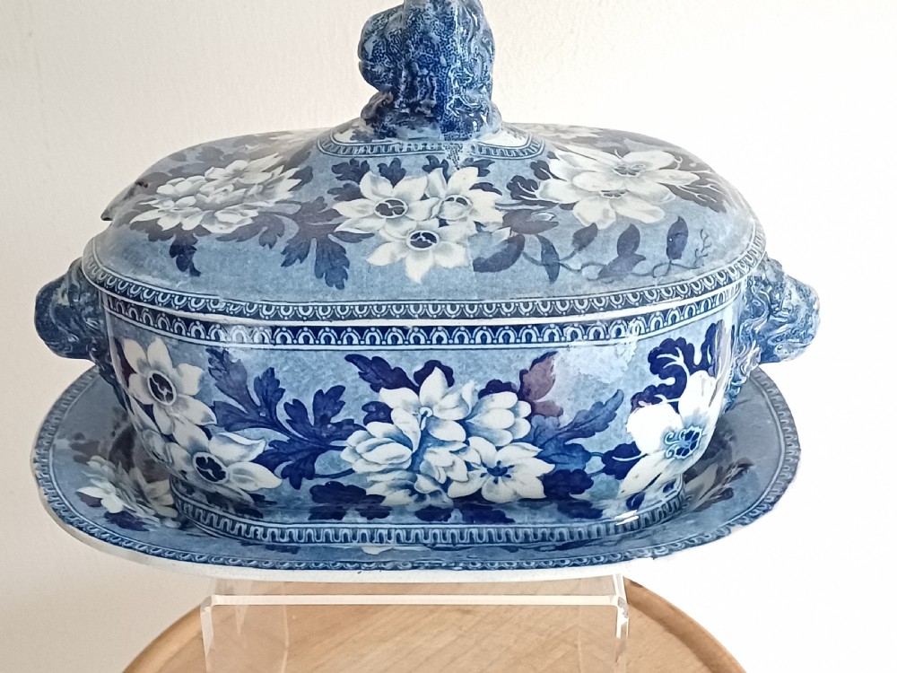 A Georgian blue and white transfer-printed ceramic sauce tureen featuring floral patterns, lion head side handles, a lion finial lid, and a matching underplate. View II
