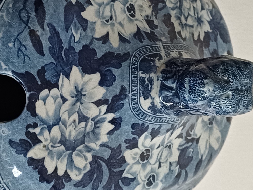 A Georgian blue and white transfer-printed ceramic sauce tureen featuring floral patterns, lion head side handles, a lion finial lid, and a matching underplate. View IV