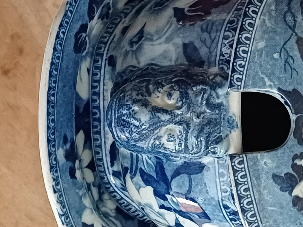 A Georgian blue and white transfer-printed ceramic sauce tureen featuring floral patterns, lion head side handles, a lion finial lid, and a matching underplate. View V